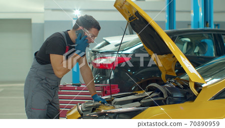 Mechanic calls customers for communication, in the car service center. Concept repair of machines fault diagnosis repair specialist, technical maintenance on-board computer. 70890959