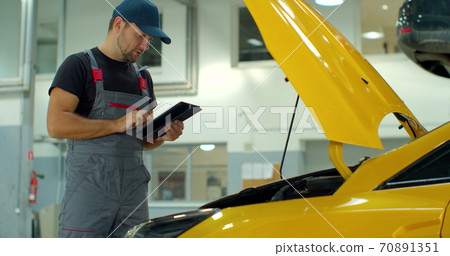 Car Service Manager Uses a Tablet Computer with an Augmented Reality Diagnostics Software. Car Service Manager Uses a Tablet Computer with an Augmented Reality Diagnostics Software. 70891351