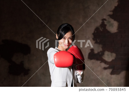 Business woman punching with boxing gloves 70893845