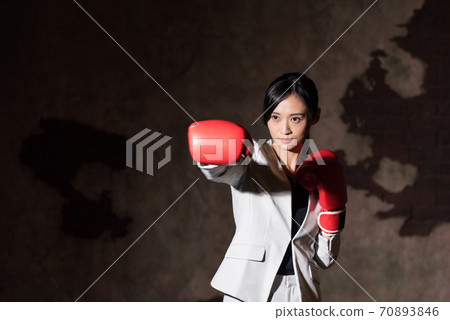 Business woman punching with boxing gloves 70893846