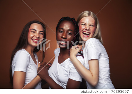 young pretty asian, caucasian, afro woman posing cheerful together on brown background, lifestyle diverse nationality people concept 70895697