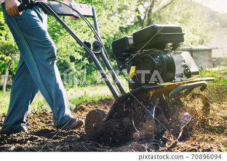A man during soil plow process by motor cultivator 70896094