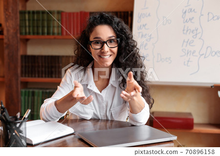 English teacher sitting at desk, explaining lesson to students English teacher sitting at desk, explaining lesson to students 70896158