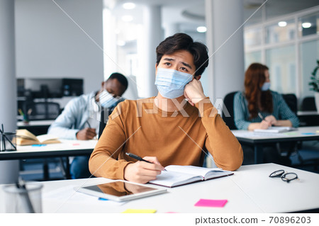 Asian male student in mask sitting at desk in class Asian male student in mask sitting at desk in class 70896203