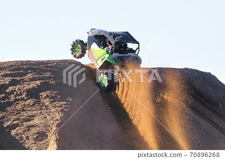 The wheels of a side-by-side spray gravel going over a hill 70896268