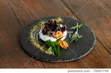 Fresh baked camembert with cranberry sauce, herbs and caramelized walnuts 70897749