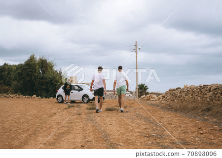 A group of people walking down a dirt road A group of people walking down a dirt road 70898006