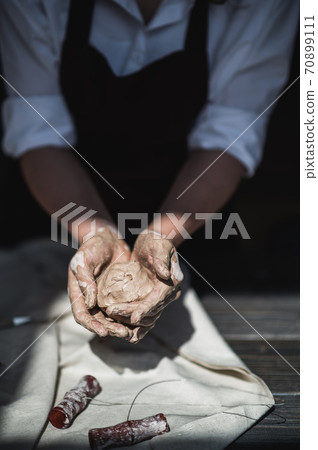 Wet hands covered with gray clay of potter holding raw piece of clay Wet hands covered with gray clay of potter holding raw piece of clay 70899111