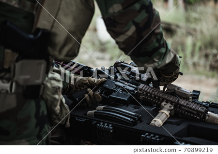 Military man with gun case takes out an assault rifle in destroyed city. Military and rescue operation concept. Military man with gun case takes out an assault rifle in destroyed city. Military and rescue operation concept. 70899219