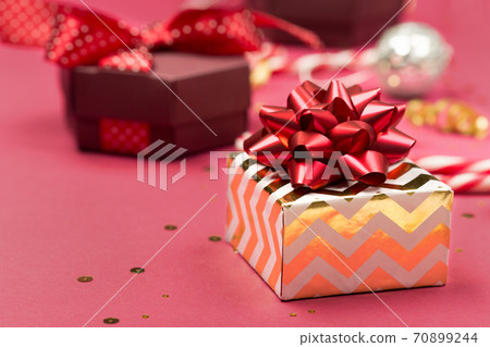 Festive Christmas gift, gold decorations, candy canes, mirror disco balls on dark pink background. Festive Christmas gift, gold decorations, candy canes, mirror disco balls on dark pink background. 70899244