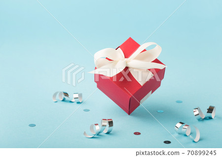 Christmas holiday card with red Xmas gift box, silver decorations, mirror disco balls on light blue background. Christmas holiday card with red Xmas gift box, silver decorations, mirror disco balls on light blue background. 70899245