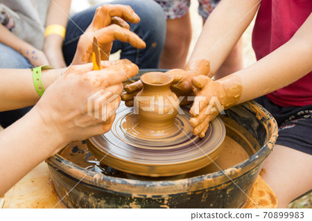 A close up view on ceramic production process on potter's wheel with children. Clay crafts with kids concept 70899983