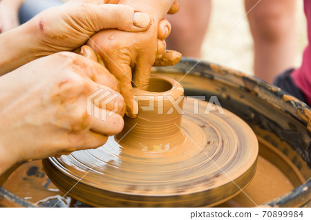 A close up view on ceramic production process on potter's wheel with children. Clay crafts with kids concept A close up view on ceramic production process on potter's wheel with children. Clay crafts with kids concept 70899984