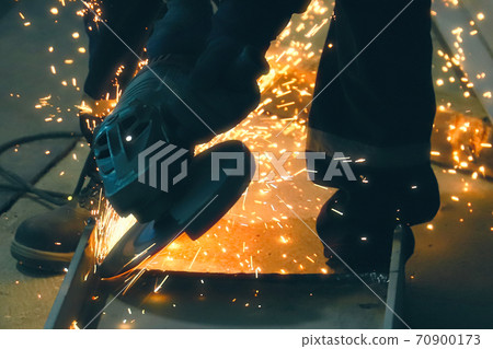 Professional worker cuts metal by angle grinder machine. Fountain of sparks. Fire safety at construction site. 70900173
