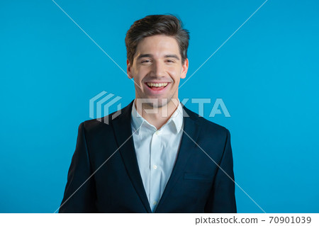 Portrait of young successful confident businessman isolated on blue studio background. Man in Portrait of young successful confident businessman isolated on blue studio background. Man in 70901039