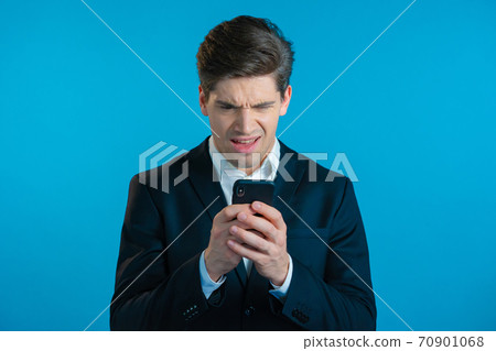 Business man receives bad notification on mobile phone. Guy is unhappy, disappointed. Technology Business man receives bad notification on mobile phone. Guy is unhappy, disappointed. Technology 70901068