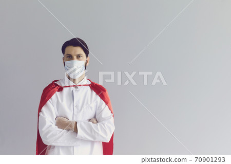 Man doctor in medical mask and costume of superhero standing and looking at camera Man doctor in medical mask and costume of superhero standing and looking at camera 70901293