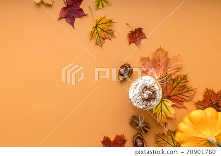 Cozy autumn style flat lay of hot pumpkin spice latte with whipped milk cream, cinamon and colorful dry leaves of october on the light orange background with empty space for logo or design Cozy autumn style flat lay of hot pumpkin spice latte with whipped milk cream, cinamon and colorful dry leaves of october on the light orange background with empty space for logo or design 70901780