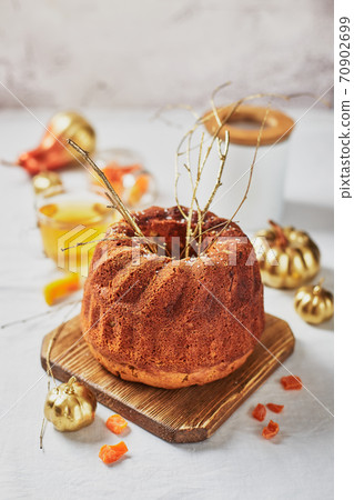 Homemade autumn carrot or pumpkin bundt cake with candied fruits, cup of tea and golden decorative pumpkins on light background. Homemade autumn carrot or pumpkin bundt cake with candied fruits, cup of tea and golden decorative pumpkins on light background. 70902699
