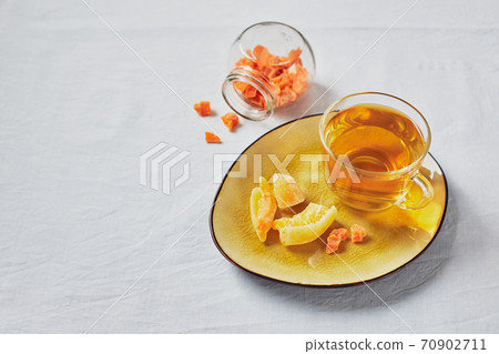 Delicious black tea in glass cup and candied fruits on yellow saucer 70902711