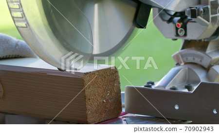 cutting off 4x4 wooden post on mitre saw close-up. Circular saw blade in motion cutting off 4x4 wooden post on mitre saw close-up. Circular saw blade in motion 70902943