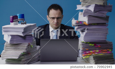 Middle-aged financial broker is working on a laptop and watching stocks 70902945