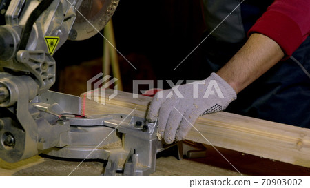 Male carpenter uses Circular Saw with laser Cutting New Baseboard for Renovation 70903002