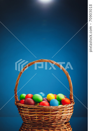 Easter color eggs in festive gift basket, blue background 70903018
