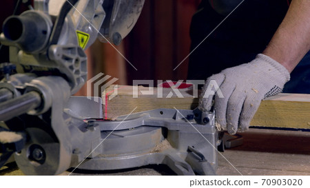 Carpenter uses Circular Saw Cutting wooden beams. Red laser line on blank Carpenter uses Circular Saw Cutting wooden beams. Red laser line on blank 70903020