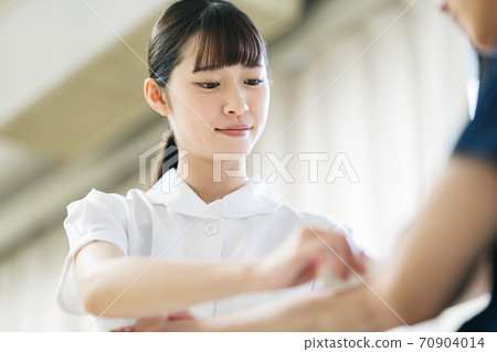 A nurse disinfecting the patient's arm 70904014