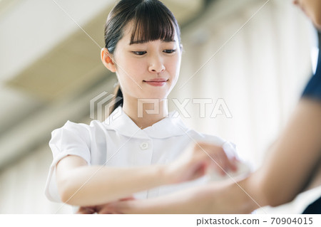 A nurse disinfecting the patient's arm A nurse disinfecting the patient's arm 70904015