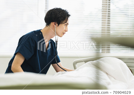 一名男醫生在病人身上放一個監聽設備 一名男醫生在病人身上放一個監聽設備 70904029