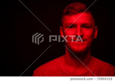 Low key portrait of bearded young man full-face looking at camera in red light Low key portrait of bearded young man full-face looking at camera in red light 70904328