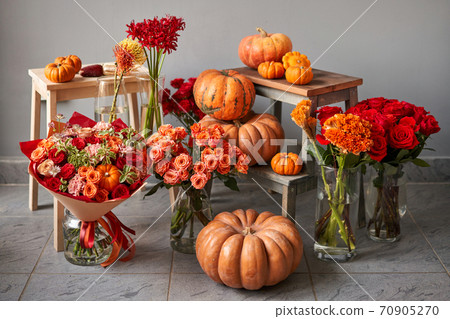 Autumn mood. Set of pumpkins and orange and red flowers for Interior decorations. The work of the florist at a flower shop. Fresh cut flower. 70905270