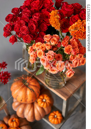 Autumn mood. Set of pumpkins and orange and red flowers for Interior decorations. The work of the florist at a flower shop. Fresh cut flower. 70905273