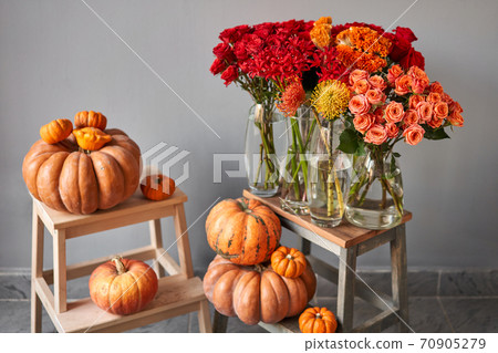 Autumn mood. Set of pumpkins and orange and red flowers for Interior decorations. The work of the florist at a flower shop. Fresh cut flower. 70905279