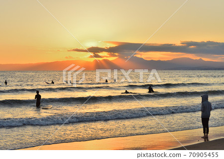 Woman looking offshore on the beach at sunset Woman looking offshore on the beach at sunset 70905455
