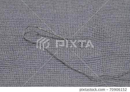 Sew a hole in the clothes with a needle and thread Sew a hole in the clothes with a needle and thread 70906152