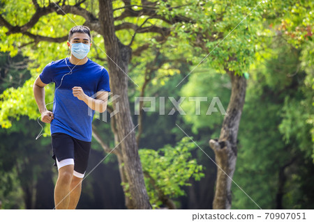 young man in face mask and jogging in the park during quarantine young man in face mask and jogging in the park during quarantine 70907051