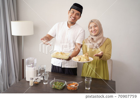 couple holding opor ayam and ketupat for lebaran couple holding opor ayam and ketupat for lebaran 70907759