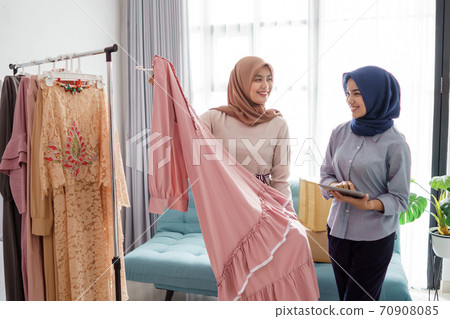 portraits of beautiful muslim women shopping for clothes and chatting with seller portraits of beautiful muslim women shopping for clothes and chatting with seller 70908085