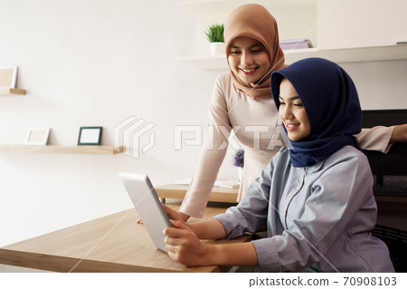 portrait of beautiful muslim women explaining project on tablet to her partner portrait of beautiful muslim women explaining project on tablet to her partner 70908103
