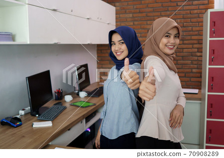 portrait of a beautiful muslim woman who is very happy with her partner with thumbs portrait of a beautiful muslim woman who is very happy with her partner with thumbs 70908289