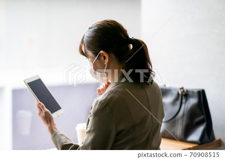 A woman who manipulates a tablet at a cafe 70908515