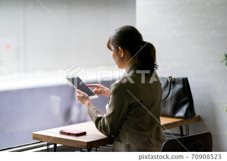 A woman who manipulates a tablet at a cafe 70908523