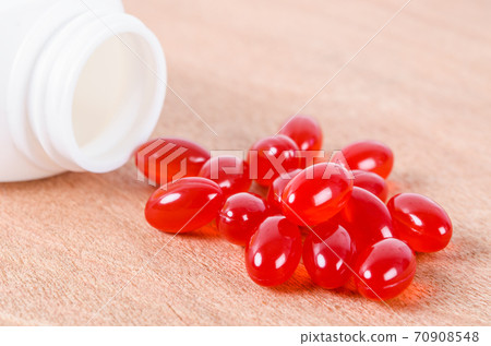 Vitamin Coenzyme Q10 and bottle on wooden background. 70908548