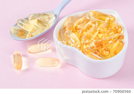 Fish oil capsules in white cup. 70908560