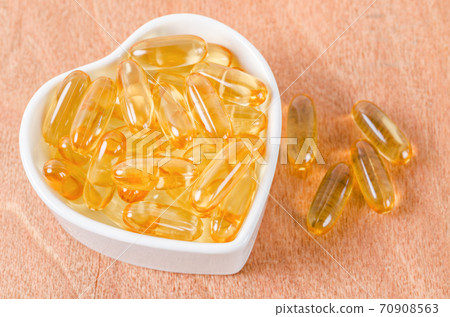 Fish oil capsules in white cup. 70908563