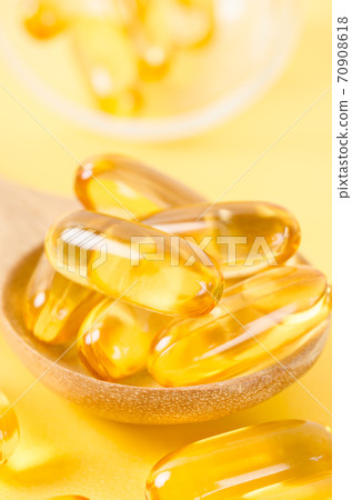 Fish oil capsules in wooden spoon. 70908618
