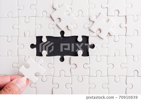 hand-holding last piece white paper jigsaw puzzle game last pieces put to place 70910839